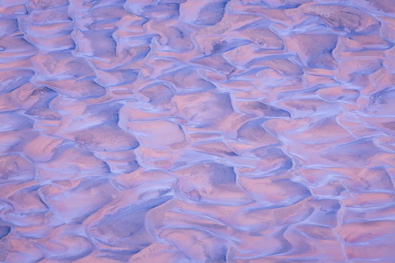 Ripples of soft colored sand take on the pink and blues of twilight on an early morning in Death Valley National Park.